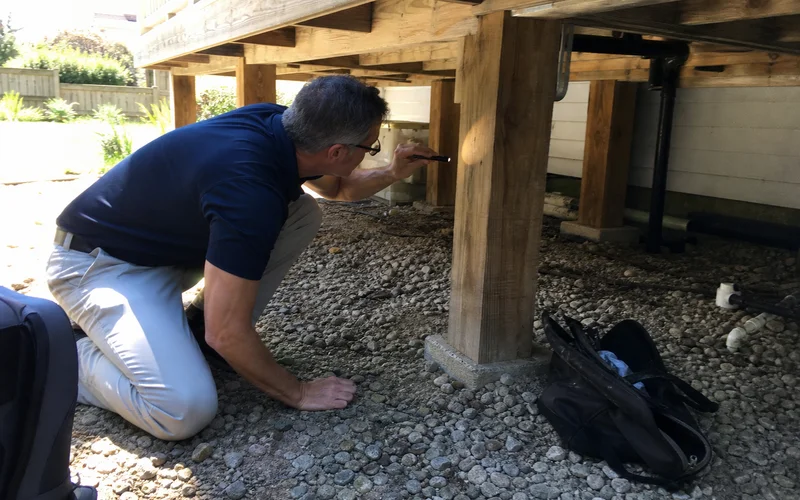 Contractor inspecting deck footings under a deck