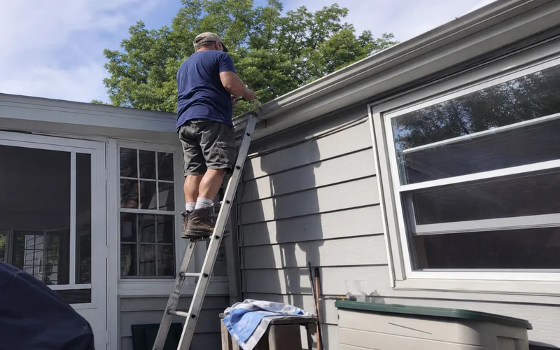 Insured handyman on a ladder repairing exterior trim confidently