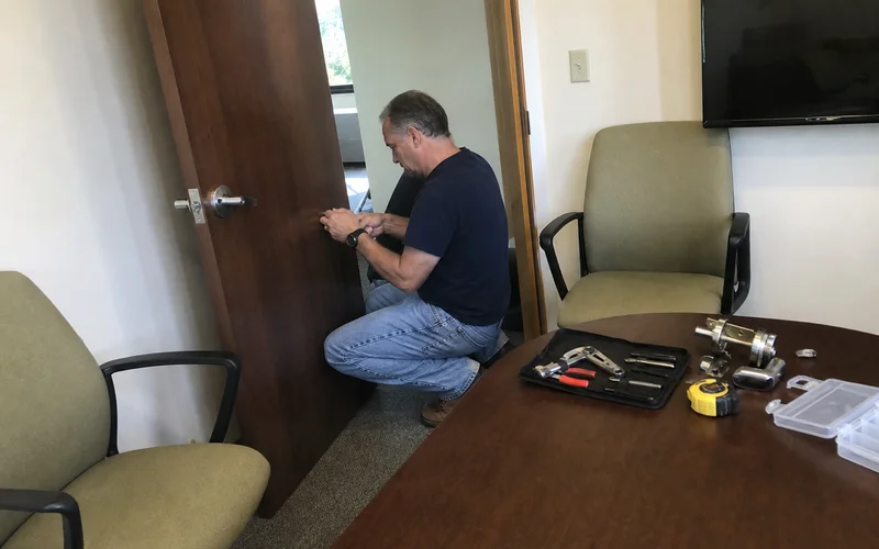Handyman repairing a conference room door in a Farmington Valley office building